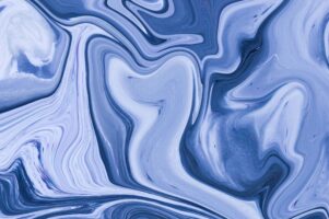 A close up photograph of a mix of blue paint colors blends together.