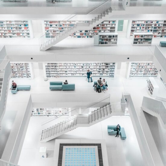 Modern white library interior with multiple levels, bookshelves, and people reading